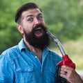 Funny man on petrol pump filling nozzles. Gas station. Portrait of bearded man hold fueling nozzle gasoline, fuel pump. Royalty Free Stock Photo