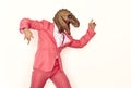 Funny man in a pink suit and a dinosaur mask dancing and having fun at a crazy party Royalty Free Stock Photo