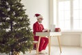 Funny man in Santa costume working on laptop computer in office with Christmas tree Royalty Free Stock Photo