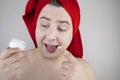 Funny man with a red towel on his head sniffs, tastes and smears a cream on his face. The concept of male self-care, spa