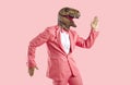 Funny man wearing pink suit and dinosaur mask dancing isolated on pink background Royalty Free Stock Photo