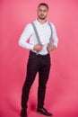 Funny man with suspenders. Cheerful friendly businessman standing on a pink background. Funny doll man.