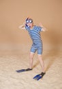 Funny man in vintage style striped swimsuit, diving mask, snorkel and flippers walking on sand Royalty Free Stock Photo