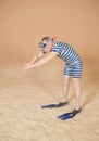 Funny man in vintage style striped swimsuit, diving mask, snorkel and flippers walking on sand Royalty Free Stock Photo