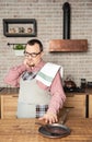 Funny man wearing pinafore with pain in his neck on the kitchen