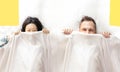 Couple hiding under the white blanket in the bed at home. Royalty Free Stock Photo