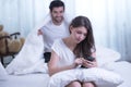 Funny married couple lying in bed and hiding under white blanket Royalty Free Stock Photo