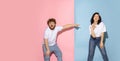 Excited couple of young funny and happy man and girl laughing studio on blue and pink trendy color background. Royalty Free Stock Photo