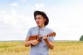 Funny men. Young beautiful caucasian man playing ukulele outside. Handsome hipster guy plays ukulele guitar on nature Royalty Free Stock Photo