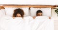 Funny couple hiding under white blanket in bed Royalty Free Stock Photo