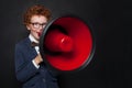 Funny mischievous child boy speaking through a loudspeaker on blackboard background. Kid with red megaphone Royalty Free Stock Photo