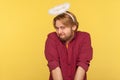 Funny modest cute bearded guy with saint nimbus over head looking at camera with shy timid expression Royalty Free Stock Photo