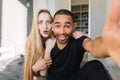 Funny moments of cute couple having fun, making selfie on bed in modern appartment. Young woman with long blonde hair Royalty Free Stock Photo