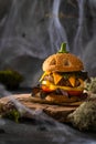 Funny monster chicken burger with salad, tomato, pepper, cutlet, cheese and pumpkin head rolls on baking paper in the form of a