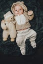 Funny 2 month old baby boy in cute costume lying on back with soft bear toy.