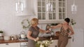 Funny mother and daughter arrange dueling with kitchen appliances in kitchen.