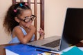 Funny multiracial small girl wearing glasses and using a laptop Royalty Free Stock Photo