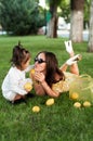 Funny mum with the daughter play with lemons lying on a grass Royalty Free Stock Photo