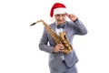 Funny Musician wears in Santa's hat holds saxophone while raising hand to head on studio background