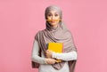 Muslim student girl in hijab holding pencil like mustache and notebooks