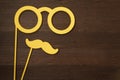 Funny mustache and glasses on sticks on a rustic brown wood background. Top view.