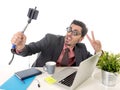 Funny nerd businessman at office desk taking selfie photo with mobile phone camera and stick Royalty Free Stock Photo