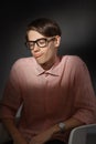 Funny nerd. Creative teen millenial portrait indoors. Funny young man with happy face expression in glasses against dark