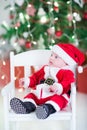 Funny newborn baby boy in Santa outfit under under Christmas tree Royalty Free Stock Photo