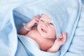 Funny newborn baby covered in blue bath towel