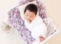 Funny newborn resting on tiny bed