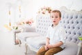 Funny nosy little boy sits on a blue sofa