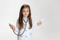 Close-up portrait of cute little girl, child in image of doctor wearing white lab coat with stethoscope isolated on