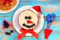 Funny oatmeal snowman with blueberry smile and strawberry nose. Festive idea for kids breakfast. New Year Christmas food top view Royalty Free Stock Photo