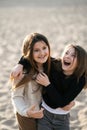 Funny overjoyed sisters having fun on weekendon the beach at sunsett, they smile and enjoy communication.