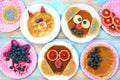 Funny pancakes for children. Cat, dog and owl shaped pancakes on white plates, blue wooden background, top view Royalty Free Stock Photo