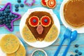 Funny pancakes for children. Pancake in a shape of owl on white plate, blue wooden background, top view. Creative idea