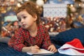 Pensive little girl writing letter to santa. kid making a wish, gift, present on new year eve. child dreaming under the christmas Royalty Free Stock Photo