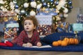 Funny pensive little girl writing letter to santa. kid making a wish, gift, present on new year eve. Royalty Free Stock Photo