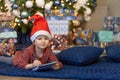 Funny pensive little girl writing letter to santa. kid in red hat making a wish, gift, present on new year eve. Royalty Free Stock Photo