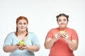 Chubby women: one woman is holding a sandwich,another one holding an apple