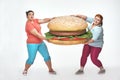 Two chubby women are holding a huge sandwich