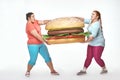 Two chubby women are holding a huge sandwich
