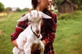 Funny picture a beautiful young asian girl farmer hugging white goat in countryside on grass. Royalty Free Stock Photo