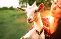 Funny picture a beautiful young asian girl farmer hugging white goat in countryside on grass. Royalty Free Stock Photo