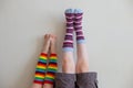 Funny picture of inverted children`s feet in very bright striped socks on a light wall.