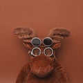 Funny pilot moose toy with vintage glasses against brown background with blank space above his head - Trendy minimal shot