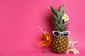 Funny pineapple with cocktail, plumeria flowers and starfish on pink background, space for text. Creative concept Royalty Free Stock Photo