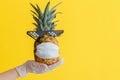 Funny pineapple face in a protective medical mask. Doctor hand in rubber glove holds summer tropical fruit pineapple in Royalty Free Stock Photo
