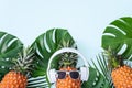 Funny pineapple wearing white headphone, concept of listening music, isolated on colored background with tropical palm leaves, top Royalty Free Stock Photo