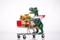 A funny plastic tyrannosaurus rides on a shopping cart full of Christmas gifts
